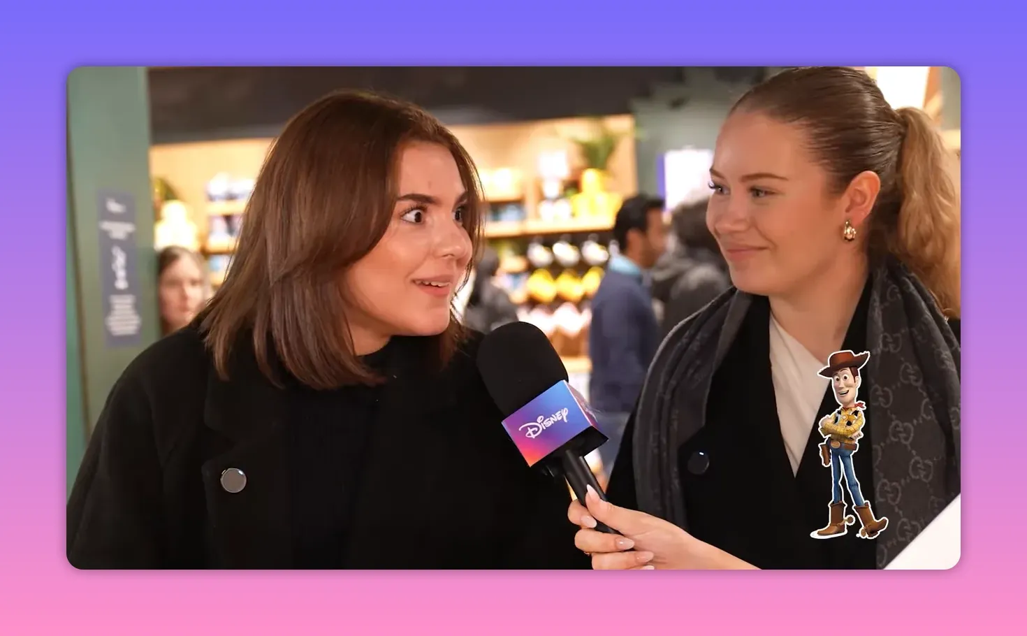 Two shoppers being interviewed with a Disney-branded microphone; one gives a wide-eyed, surprised expression while the other smiles.