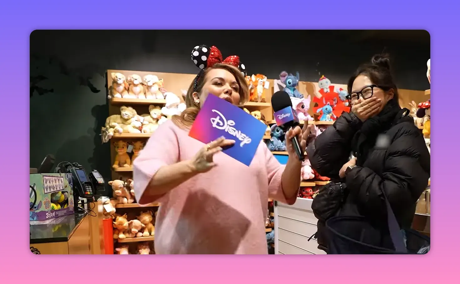 Host wearing Minnie ears holding a Disney card and microphone while a shopper laughs and covers her mouth, showing a fast-paced in-store interaction.