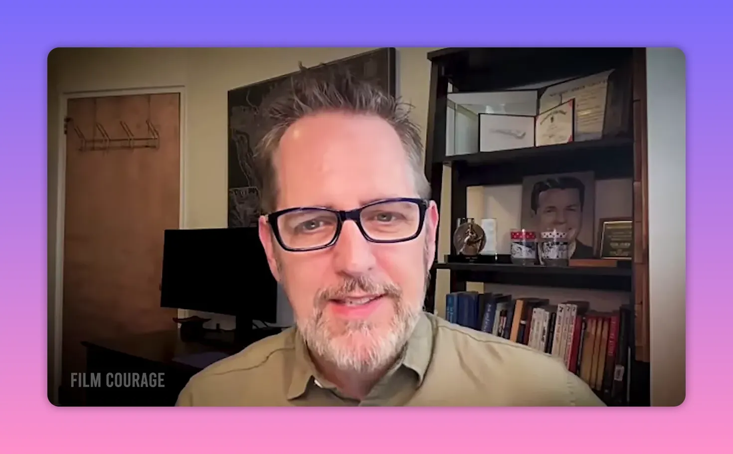 Smiling man with glasses speaking on camera in a home office with bookshelf background