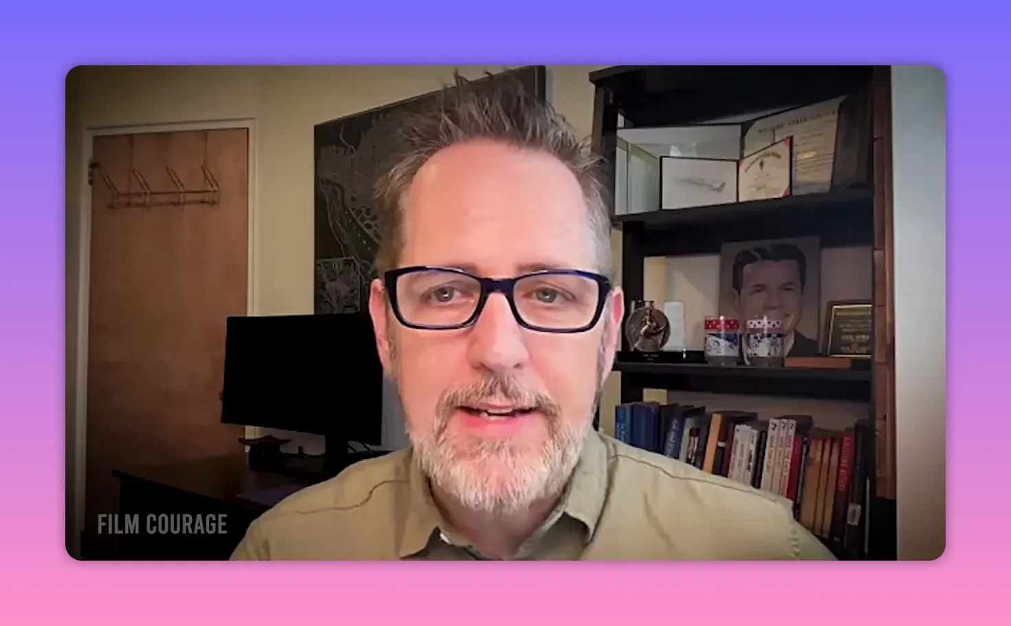 clear, well-lit shot of a man with glasses speaking in a home office with books and awards on a shelf behind him
