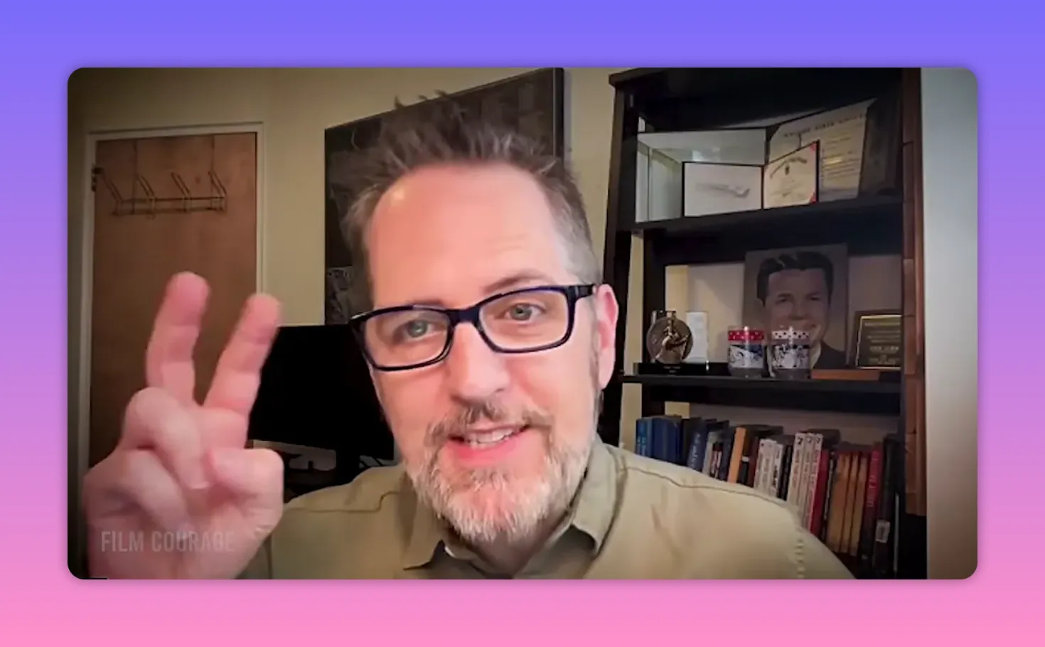 Speaker in home office smiling and holding up two fingers as a gesture while talking.