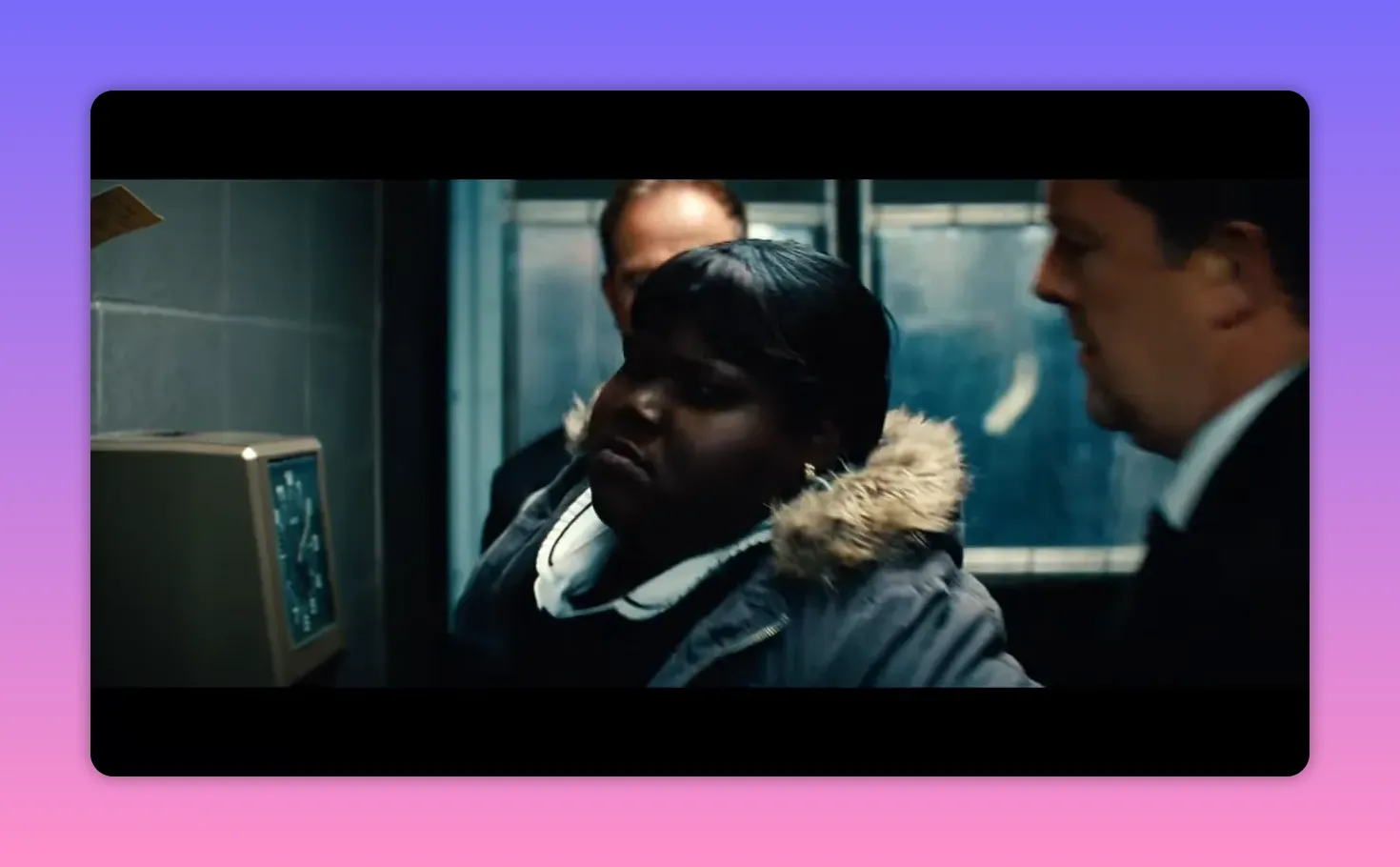 woman in a hooded coat flanked by men in suits in a narrow room, appearing confronted