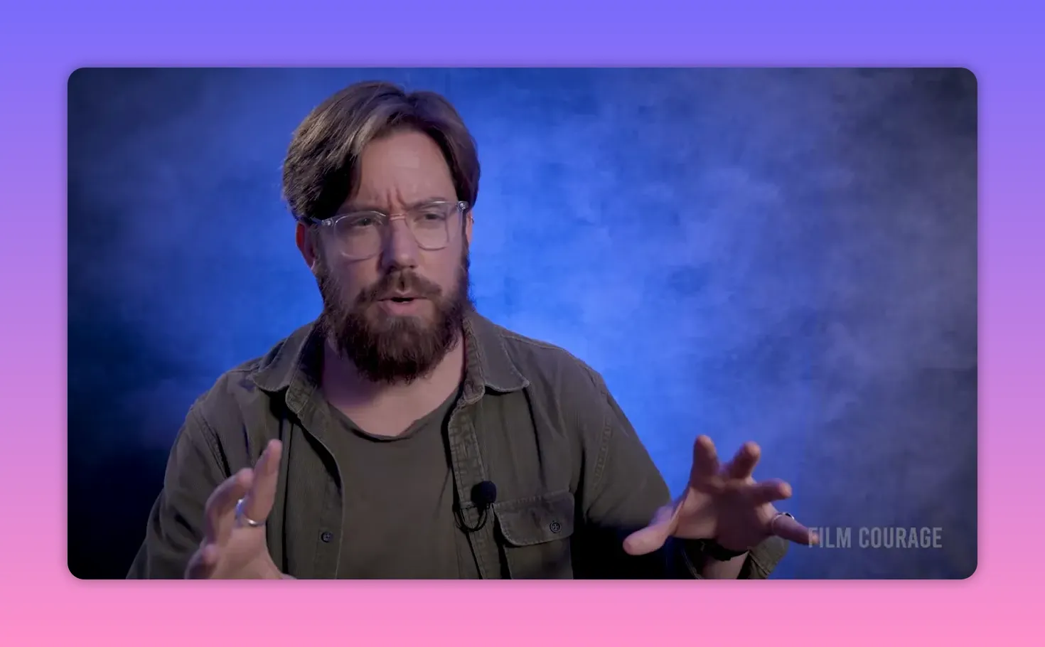 Filmmaker explaining film formats and texture, gesturing with hands against a blue textured backdrop.