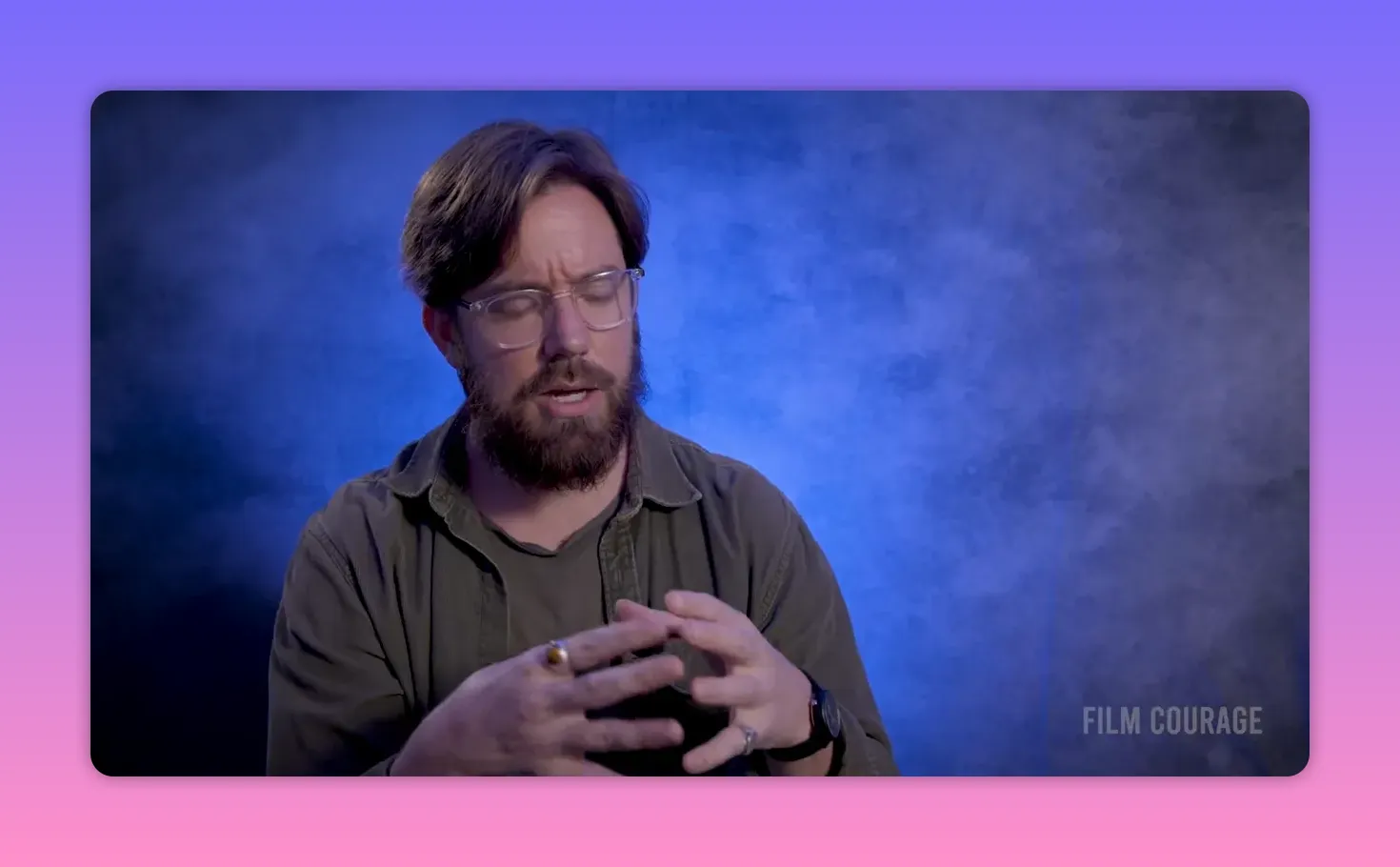 Filmmaker with eyes closed in a brief meditative moment against a blue textured backdrop, hands forming a small shape.