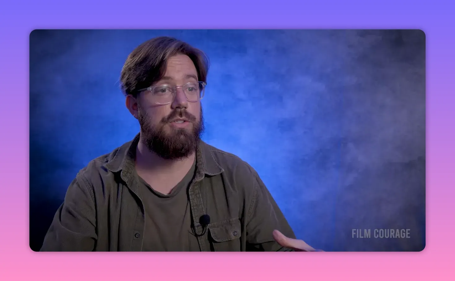 Filmmaker looking slightly right, speaking with a calm expression against a blue mottled background.