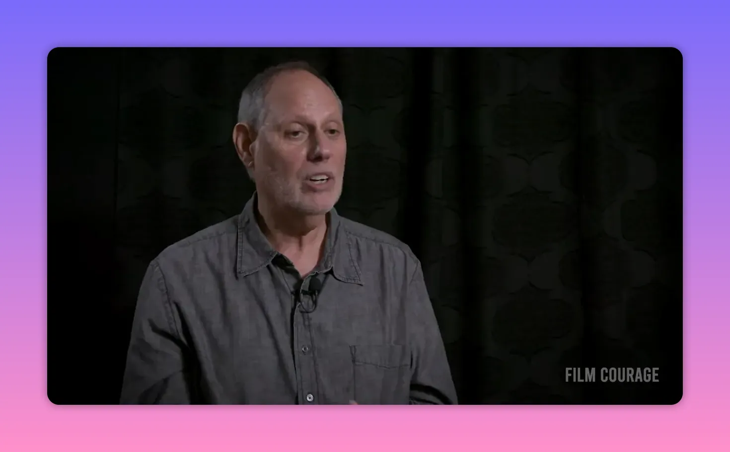 Composed mid-shot interview subject explaining the practical difference between story and plot against a dark backdrop