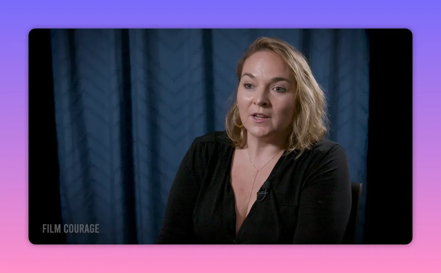 Mid-shot of a filmmaker speaking directly, clear expression, blue curtain background.