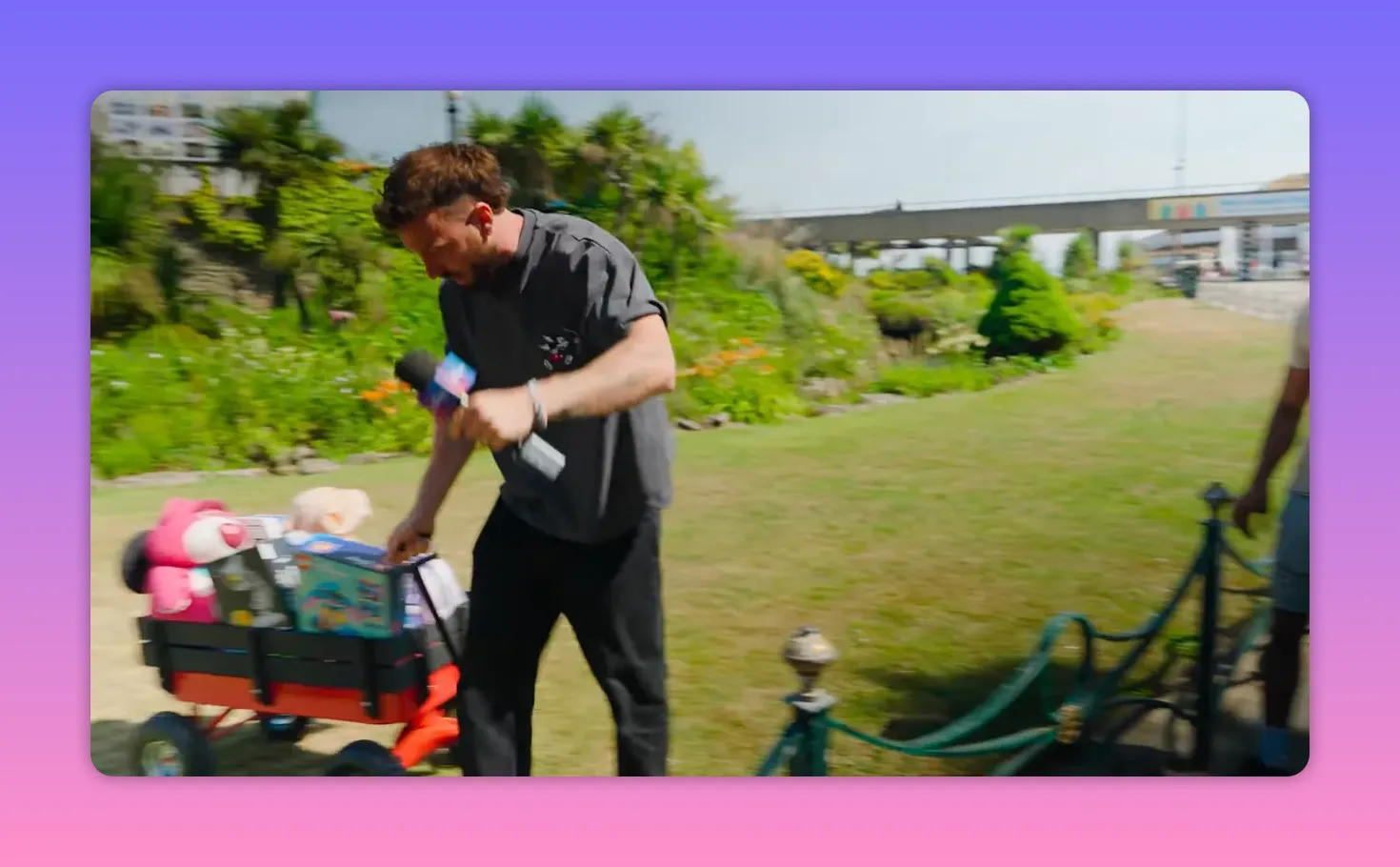 Host pulling a small trolley filled with colourful toys while holding a microphone