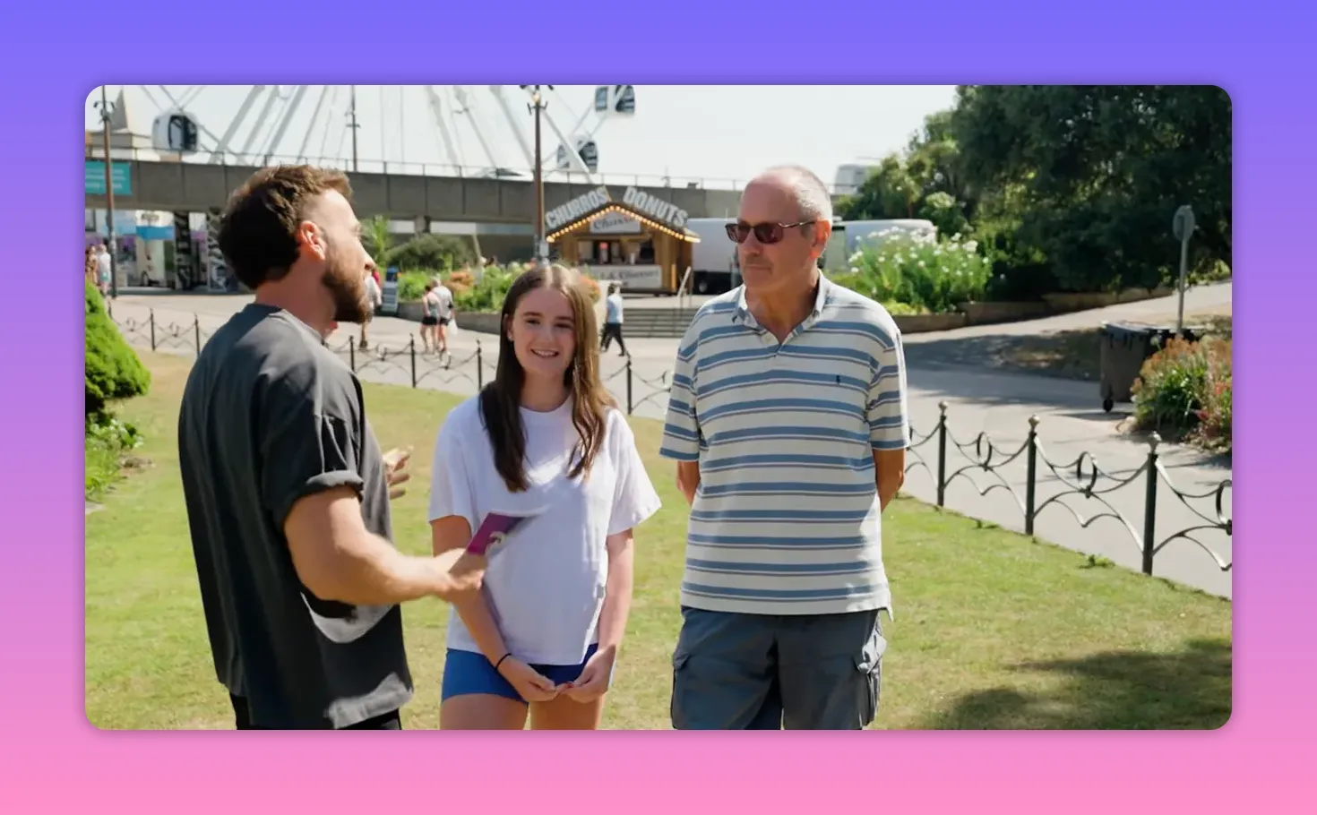 Grandfather and granddaughter standing together smiling while the host speaks to them in a park