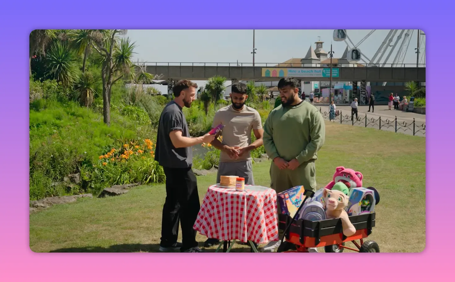 Outdoor picnic table with stacked bread slices, a jar of peanut butter and a trolley of prizes beside it.