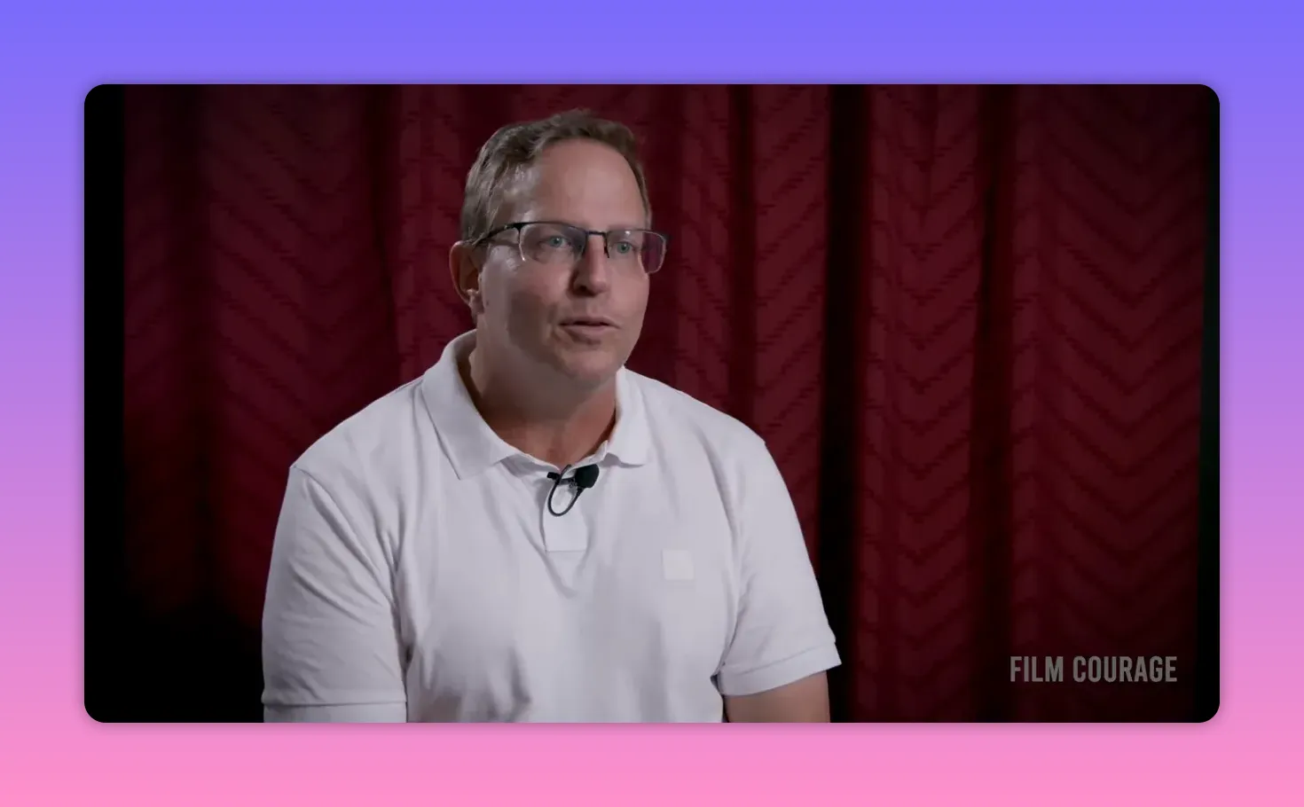 High-quality interview portrait of speaker in white polo with lapel mic against a maroon curtain backdrop and Film Courage watermark &mdash; clear, well-lit mid-shot
