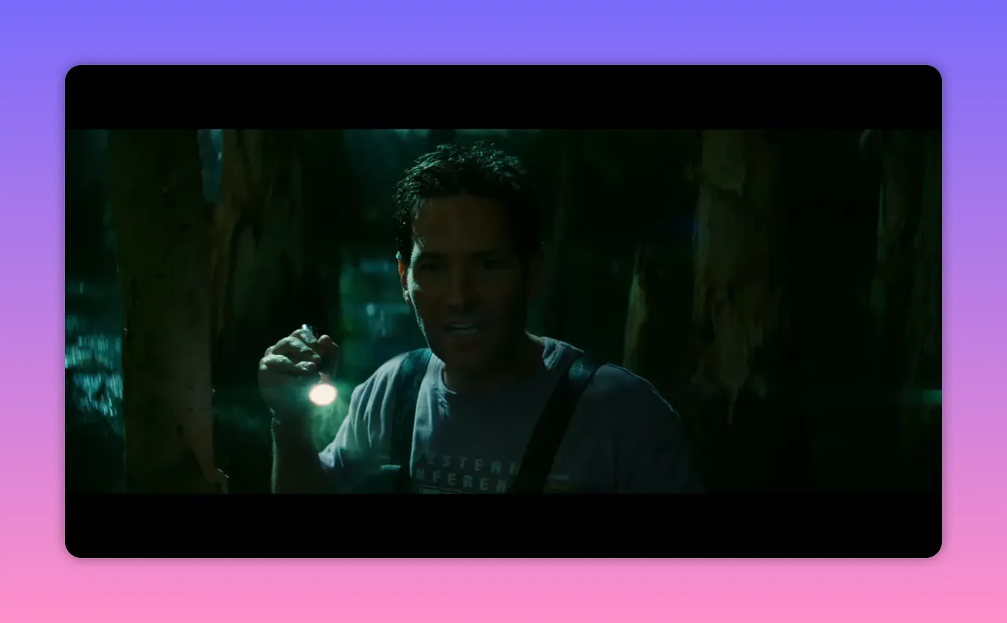 Lead actor holding a flashlight while moving through dark, swampy trees at night.