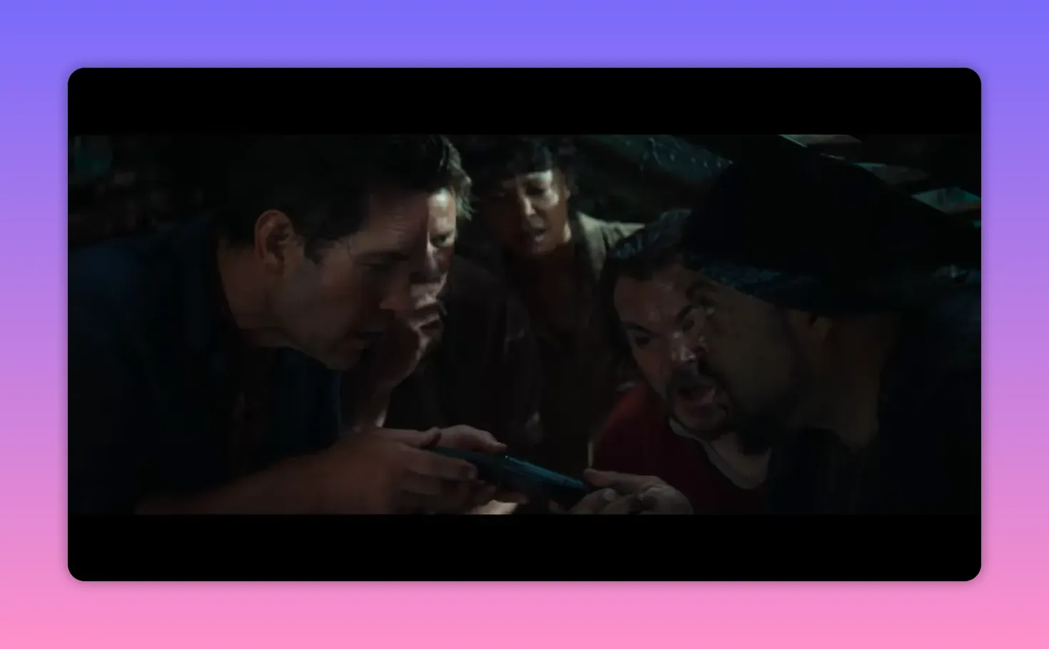 Four crew members huddled closely in dim light, intently examining a small device