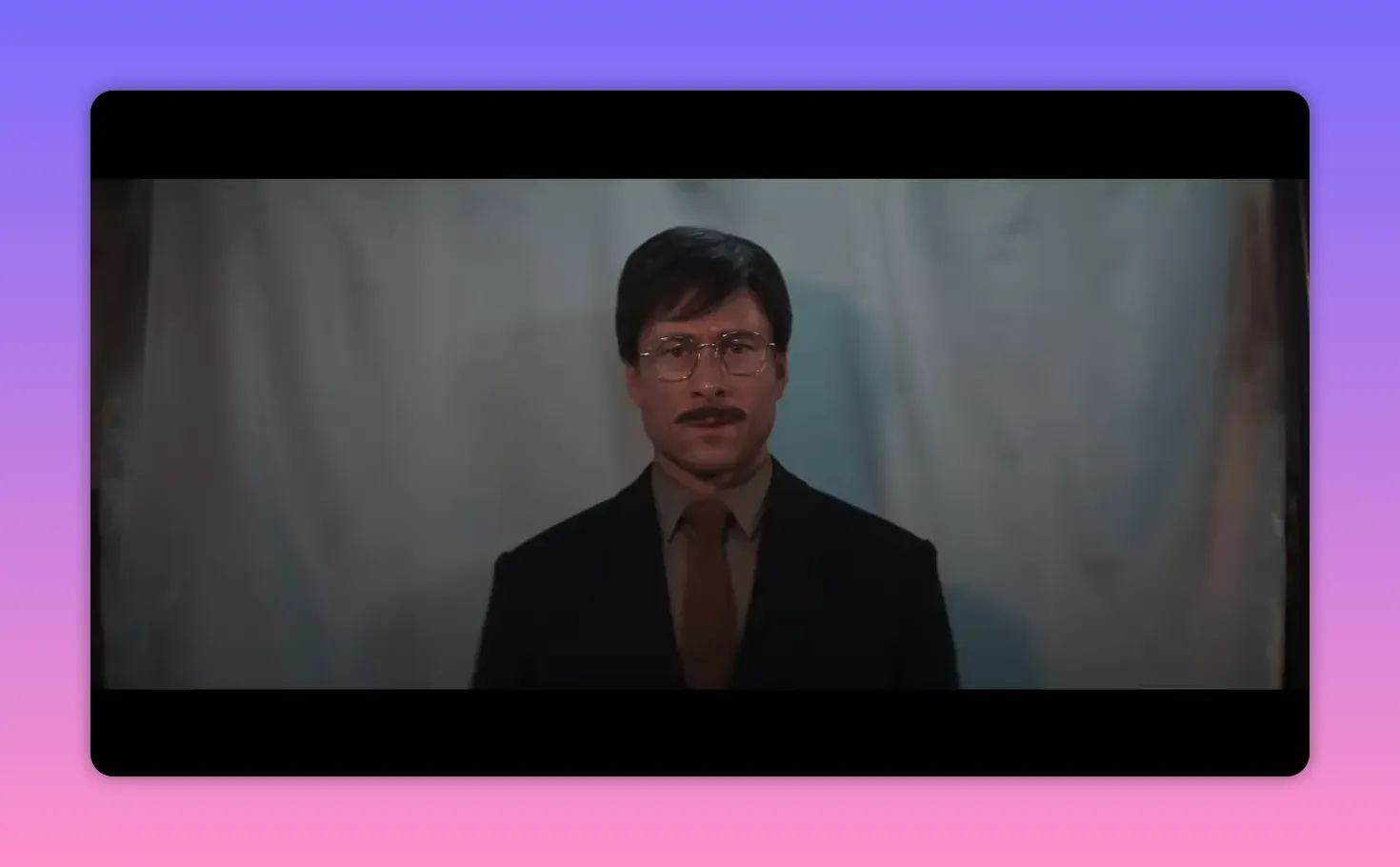 Formal portrait of a composed man in a suit standing against a plain backdrop