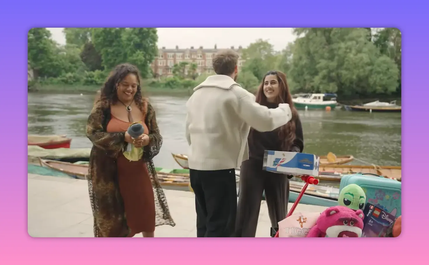 Three contestants by the river with prize toys and a scooter visible in the foreground