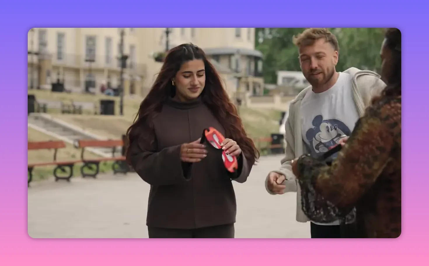 Contestant examining a blindfold while the host looks on, preparing for the touch-identification round.