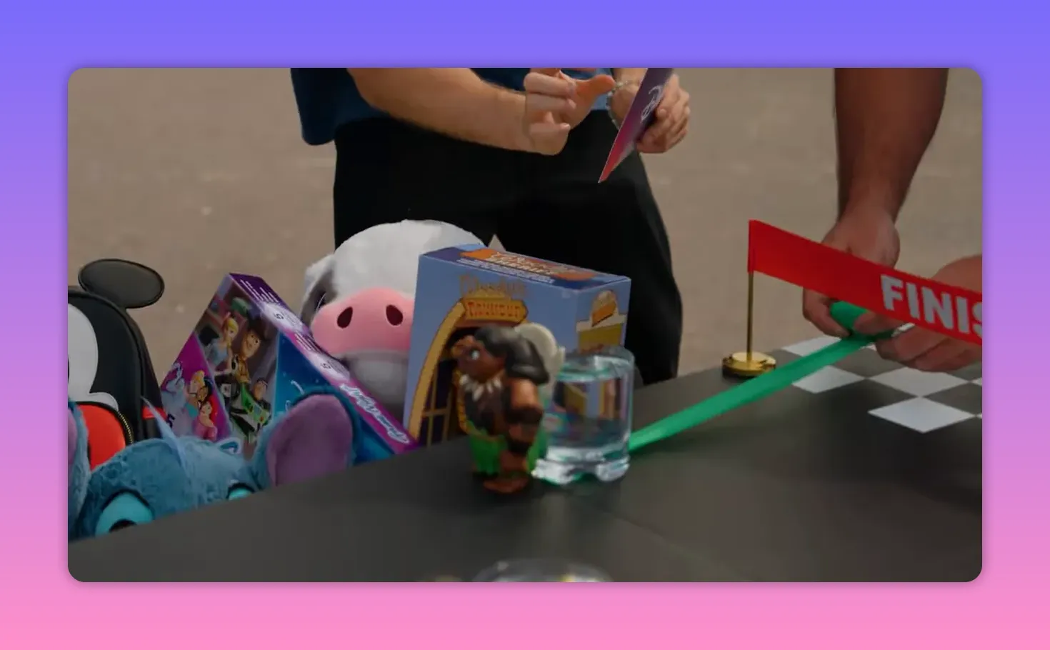 Close-up of a toy figure next to a water-filled cup and a finish banner on the rolling challenge table