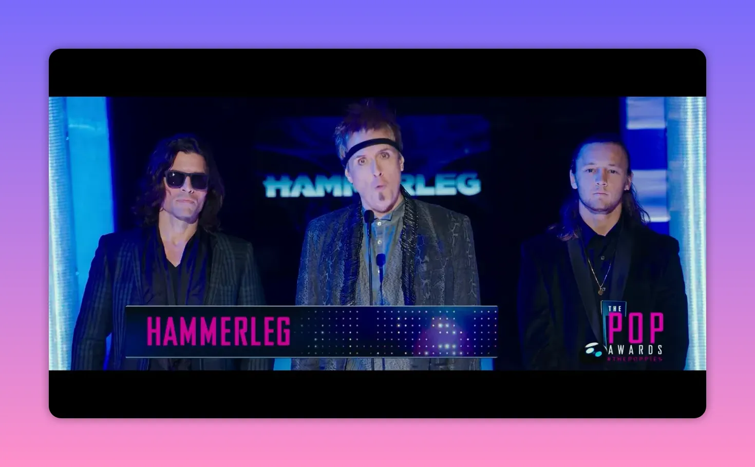 Three on-stage presenters announcing at the Pop Awards with a HAMMERLEG banner