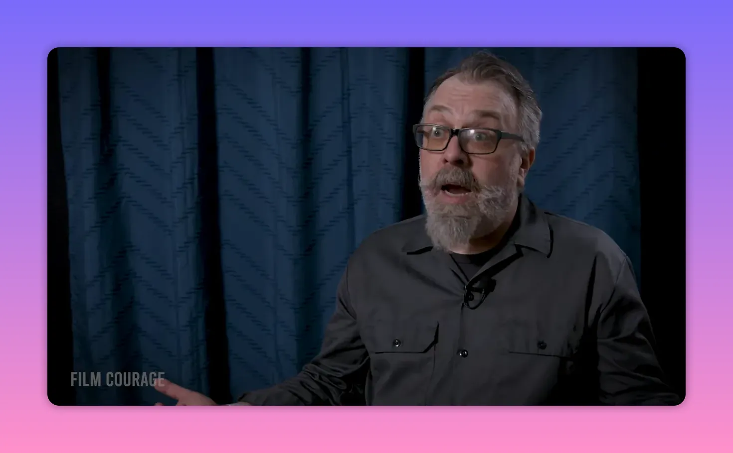 Interview subject with open hand gesture and expressive face, blue curtain backdrop