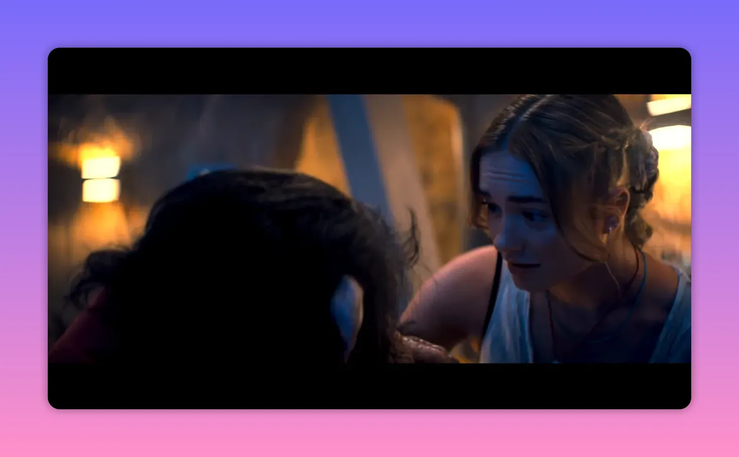 Lucy leaning over and reaching toward the head of a dark-haired figure in a dimly lit room, showing close interaction