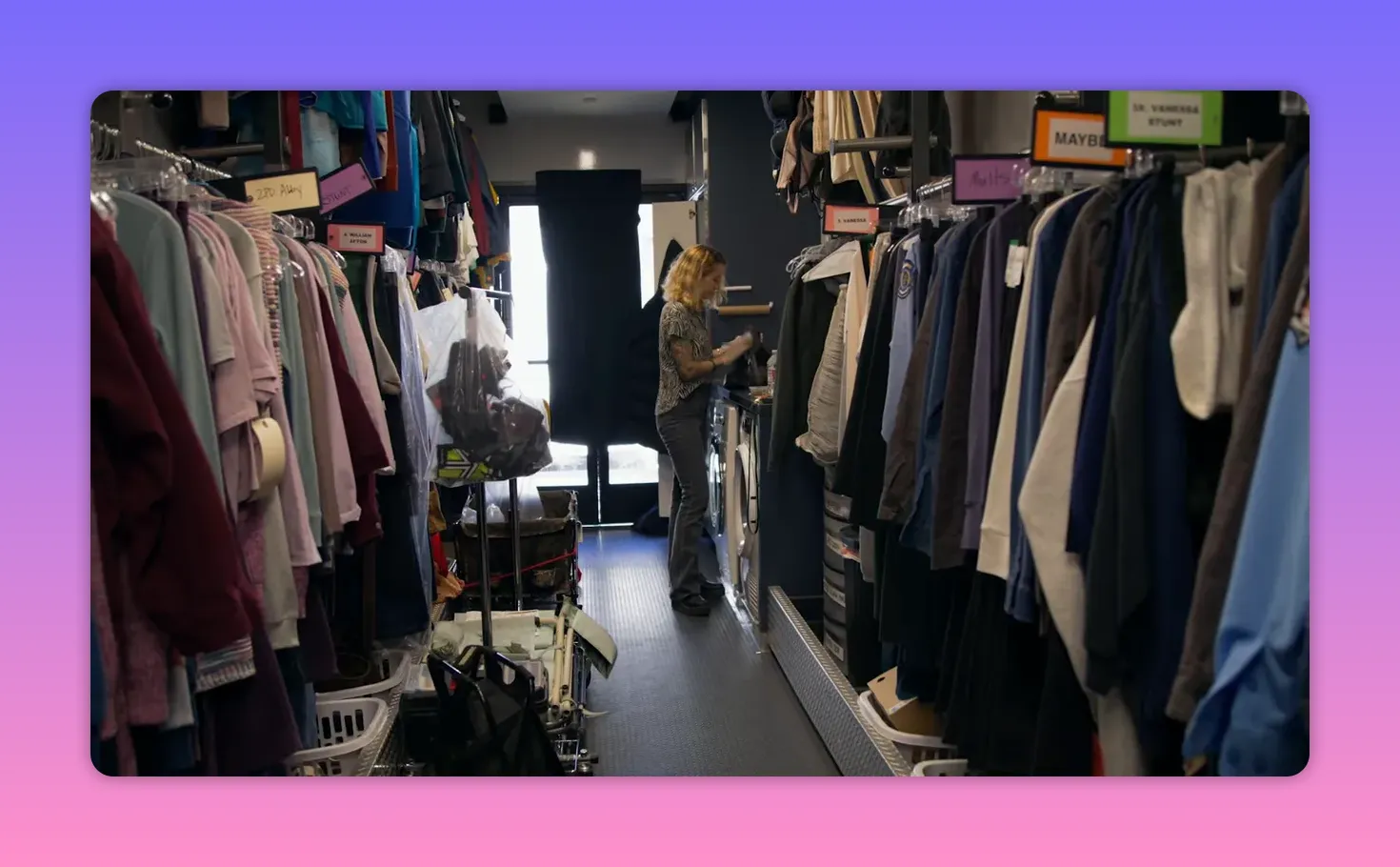 Interior of a wardrobe truck showing organized clothing racks and a costumer prepping items.