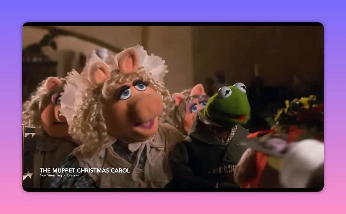 Kermit the Frog and Miss Piggy in period costume seated together in a warm Cratchit family scene.