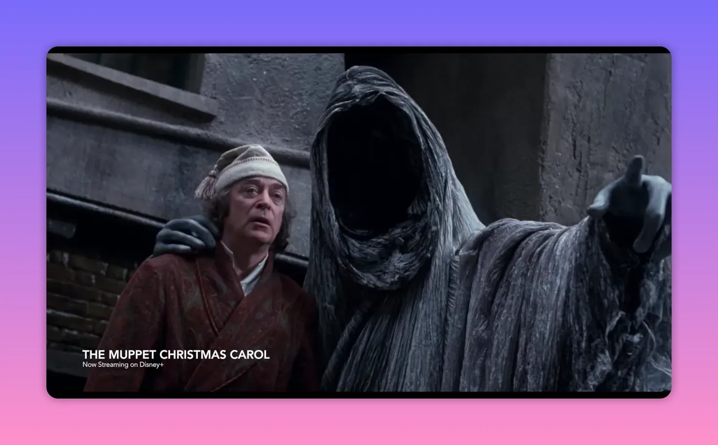 The faceless Ghost of Christmas Yet to Come alongside Scrooge in a grey, stone setting, the ghost pointing ominously