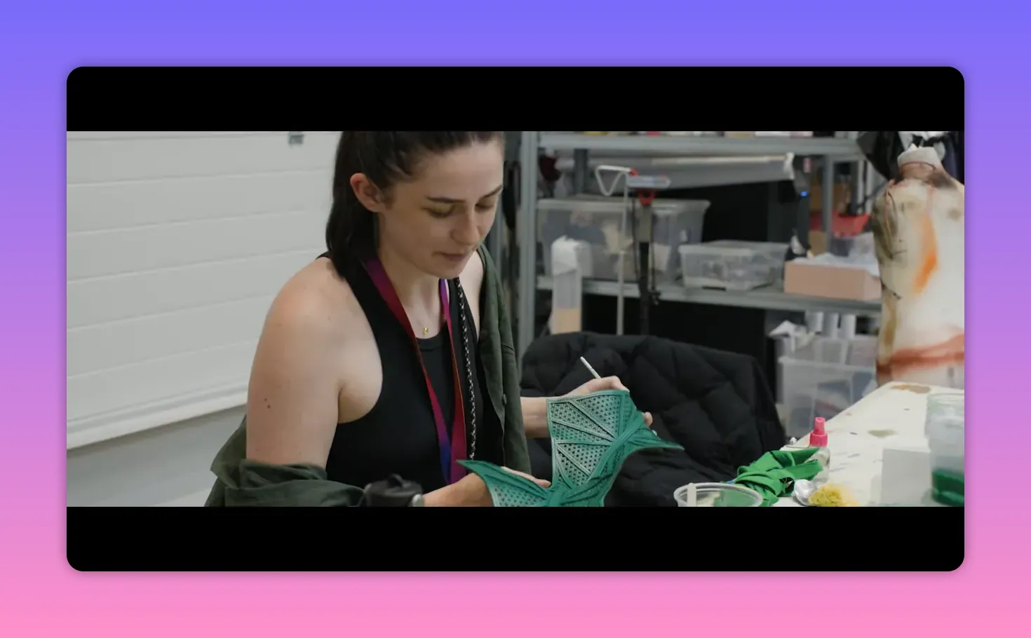 artisan painting and finishing a green costume piece at a workbench, close-up on the handwork