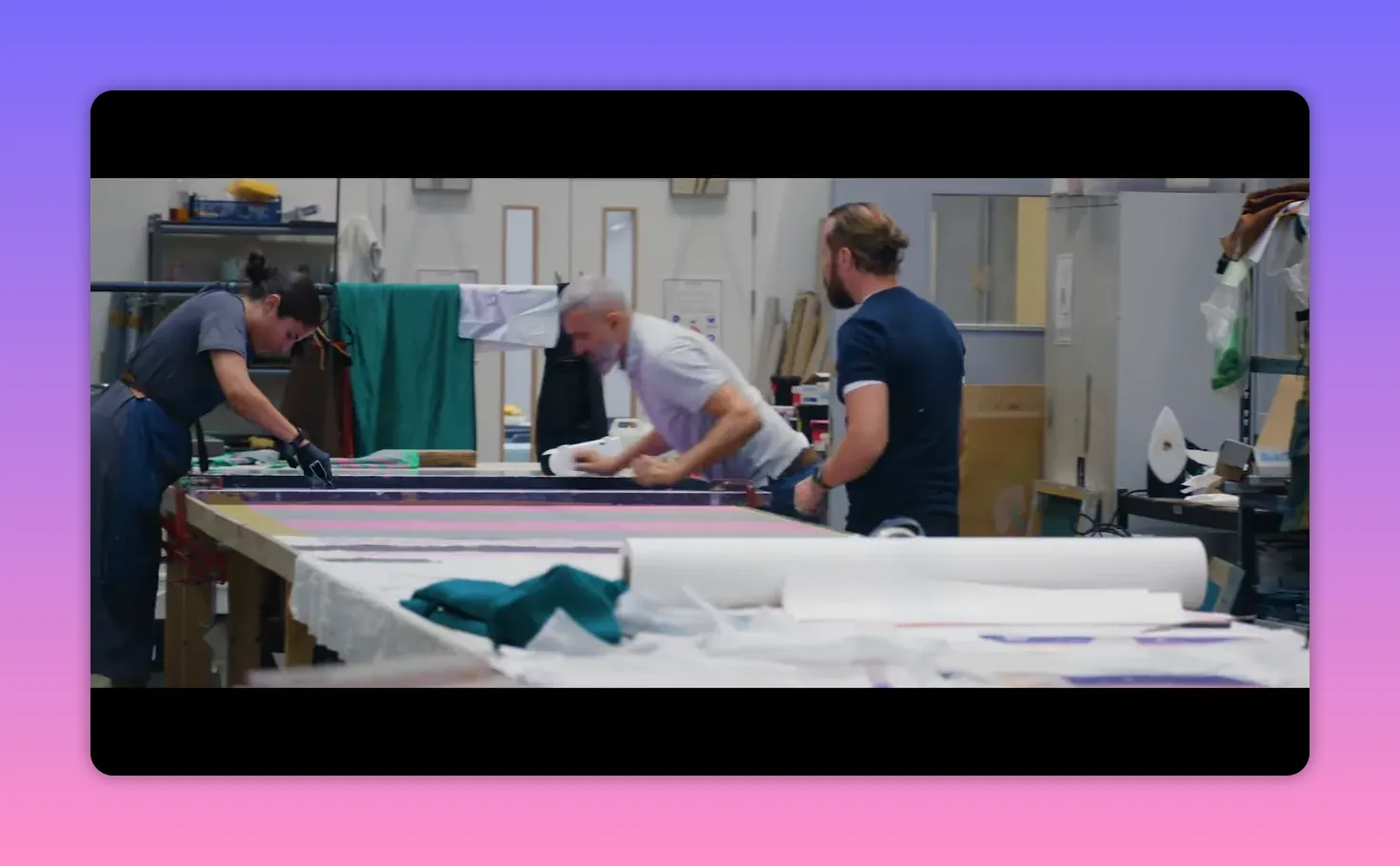 Workshop team collaborating around a long table, preparing and checking printed textiles