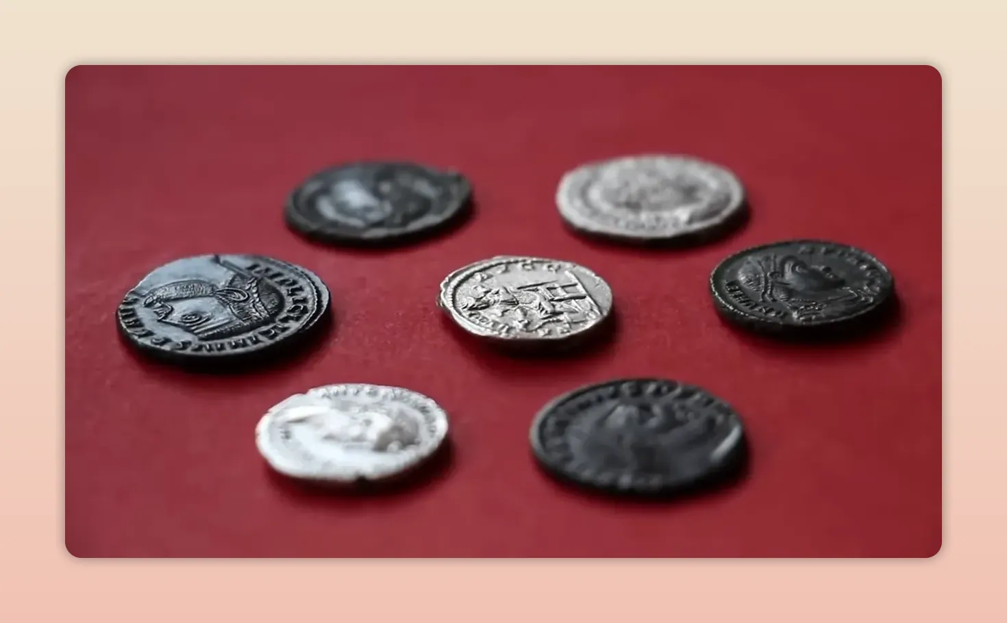 Silver and dark Roman coins arranged on a red surface