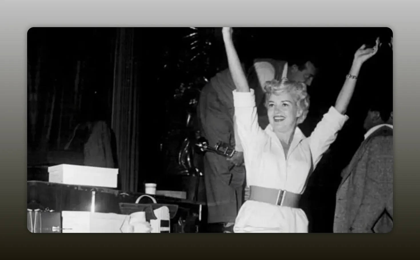 Clear black-and-white photograph of Betty Grable smiling and raising her arms onstage, good contrast and detail