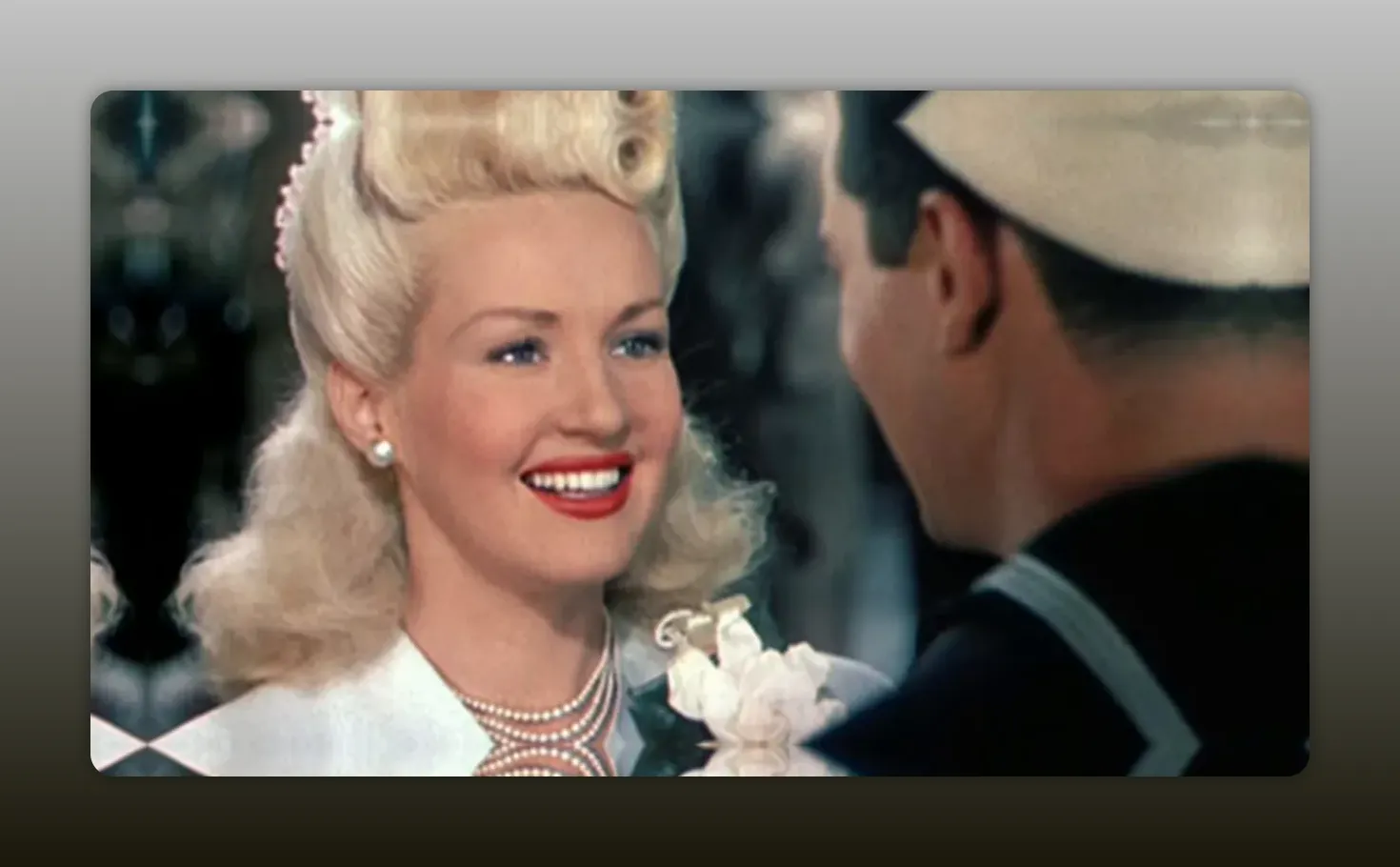 Wide color shot of Betty Grable smiling at a sailor, representative Technicolor film still.