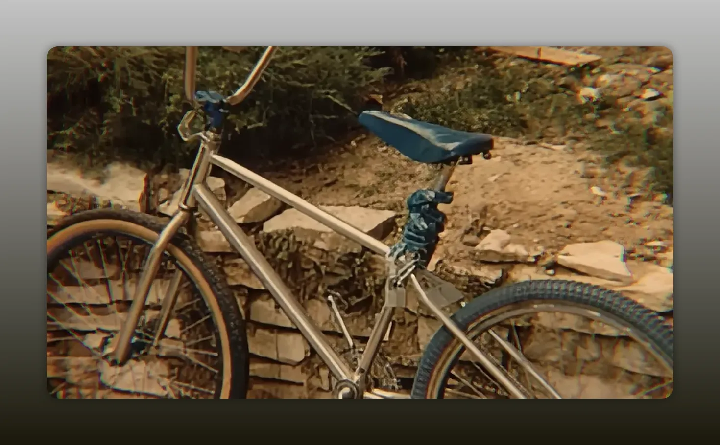 Clear photo of a bicycle propped against a low stone wall, showing seat and wheels