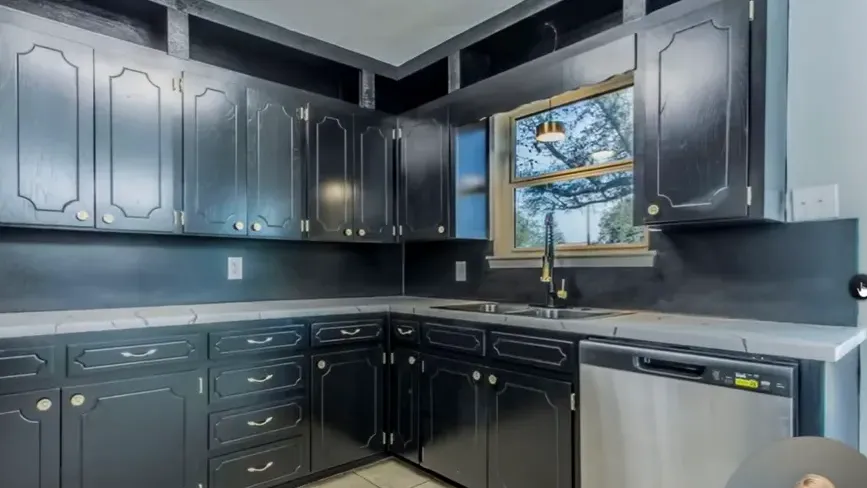 Dark kitchen with older cabinets and tile floor in an affordable Morgan's Point home