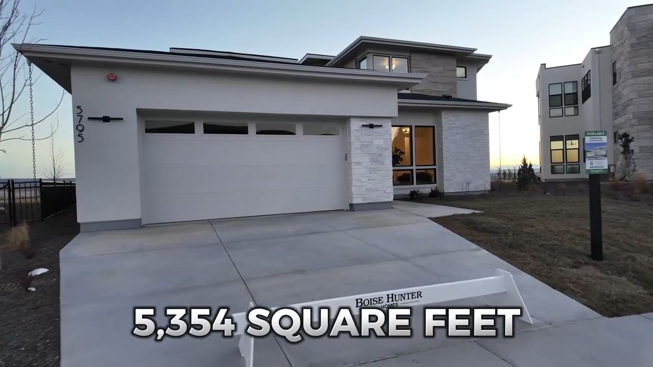 Contemporary exterior lighting, stonework, and a broad garage Harris North Boise Home