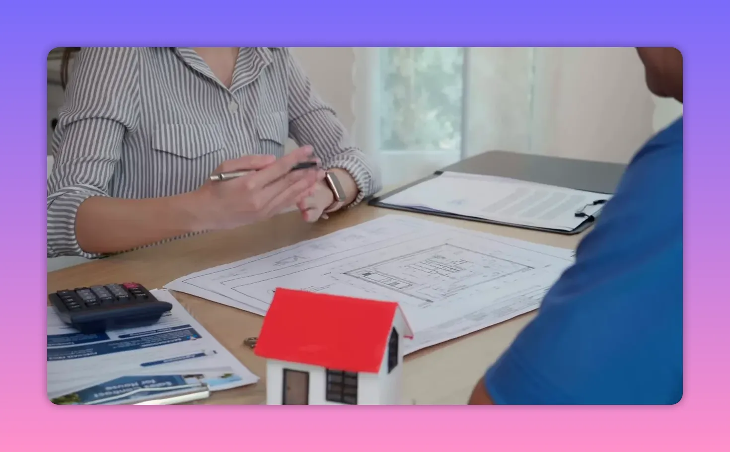 Agent and buyer reviewing mortgage paperwork at a table with a house model