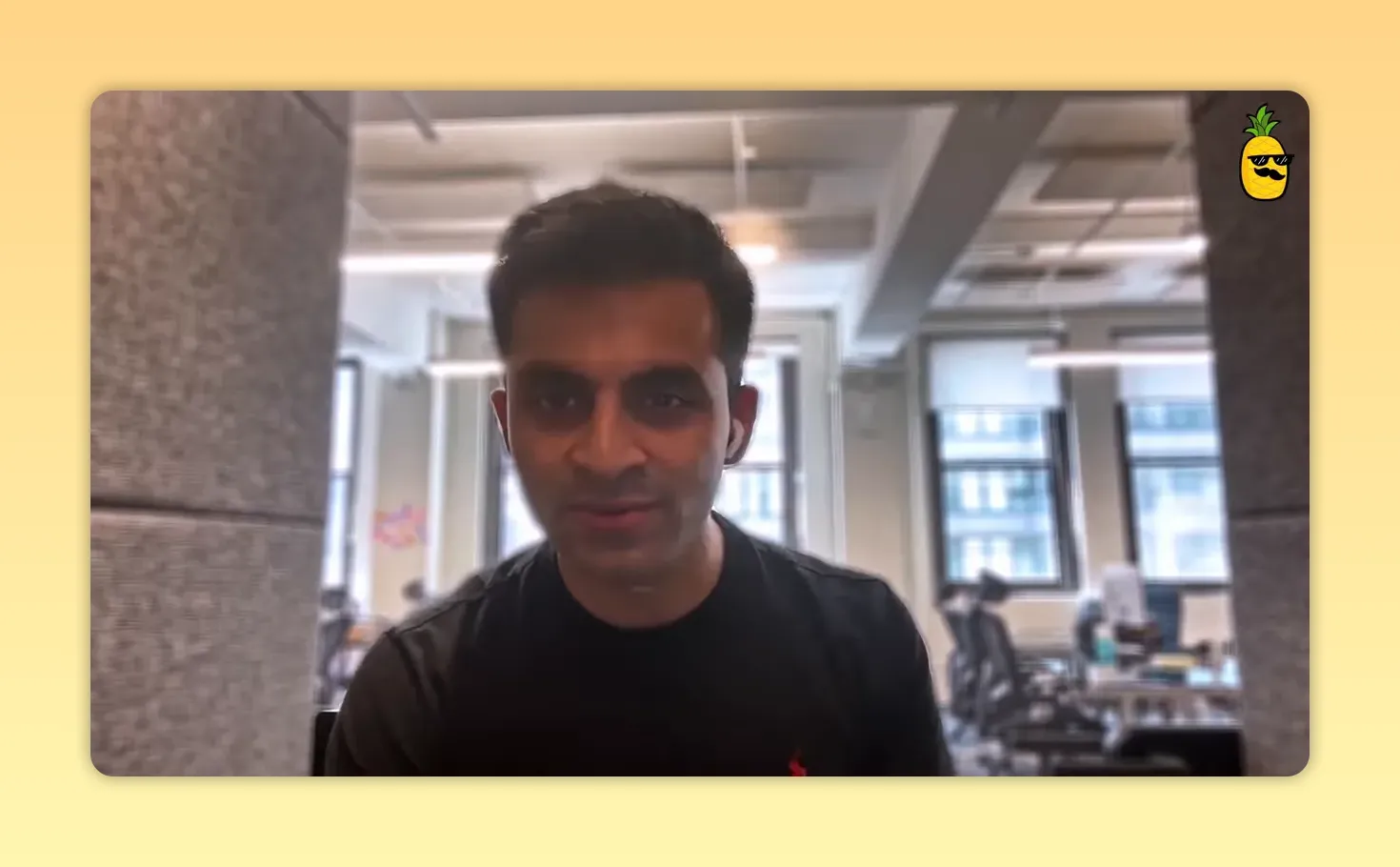 Straightforward headshot of a speaker in an office with windows behind them, looking at the camera