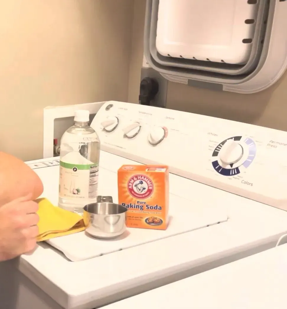 Supplies for washing machine cleaning: baking soda, vinegar, measuring cup, cloth