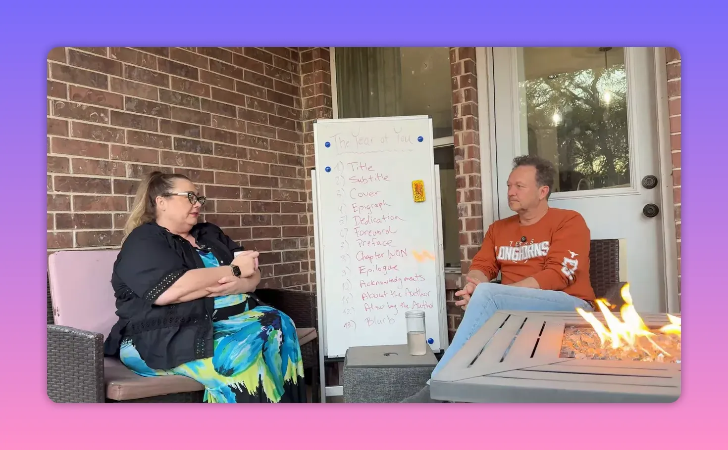 Centered whiteboard titled 'The Year of You' with a numbered list between two seated people on a patio; minimal flame glare and high clarity.
