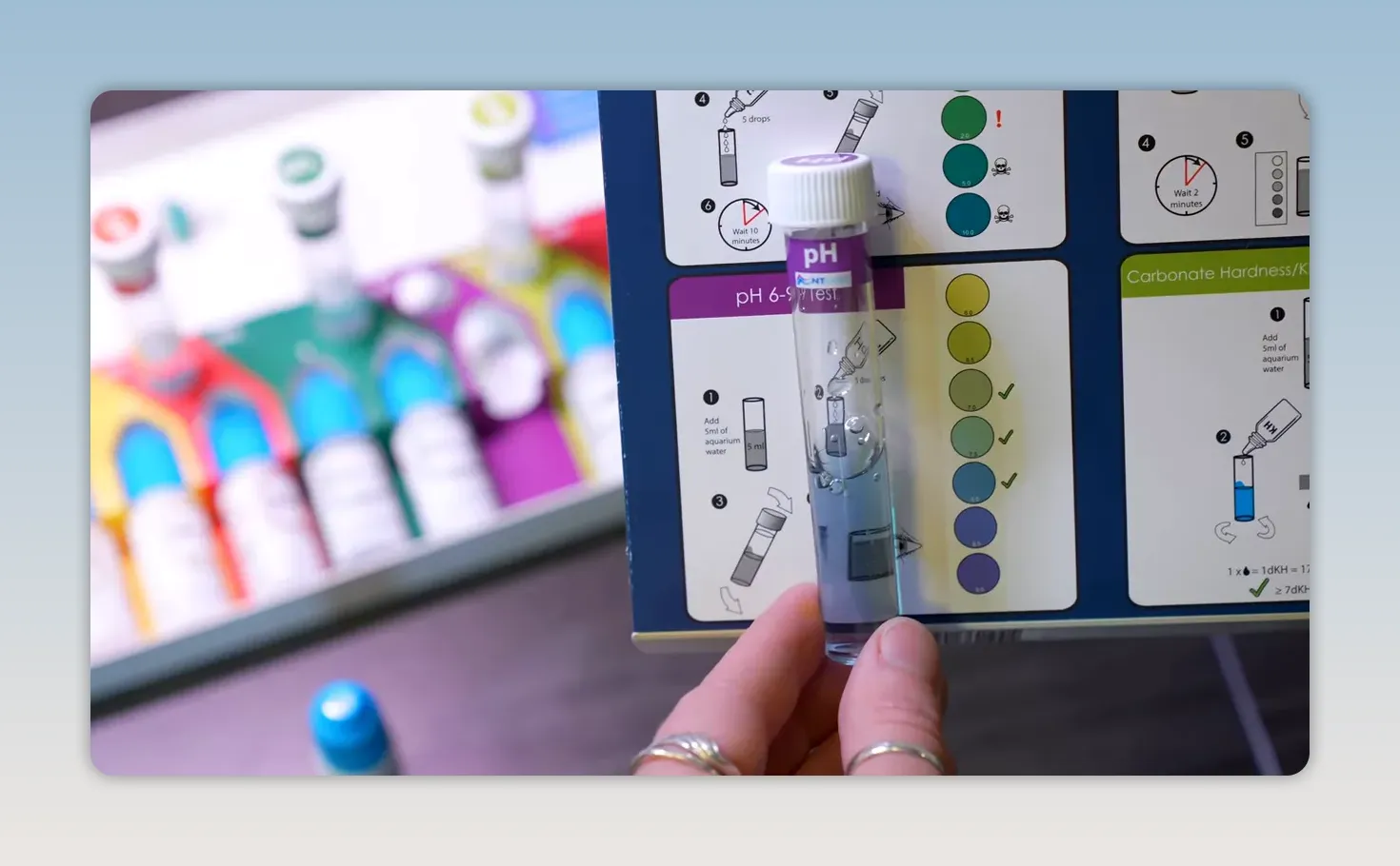 Blue aquarium water sample held against the pH colour chart