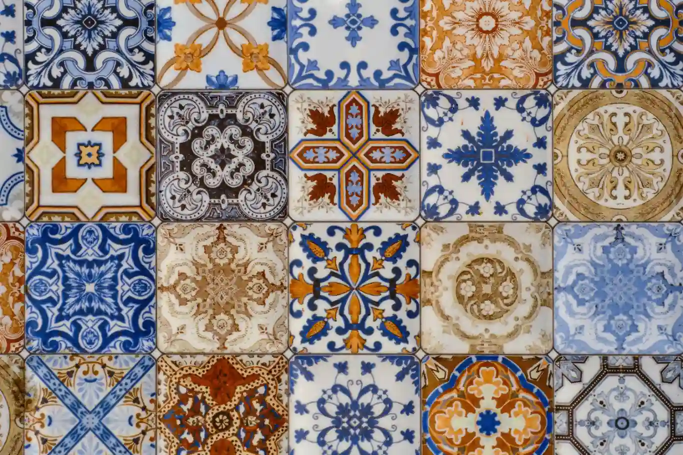 Close-up of colorful, intricate Portuguese ceramic tiles with blue, orange, and brown patterns.