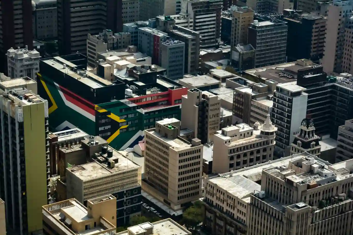 Aerial view of Johannesburg city center with buildings adorned by a large South African flag mural.