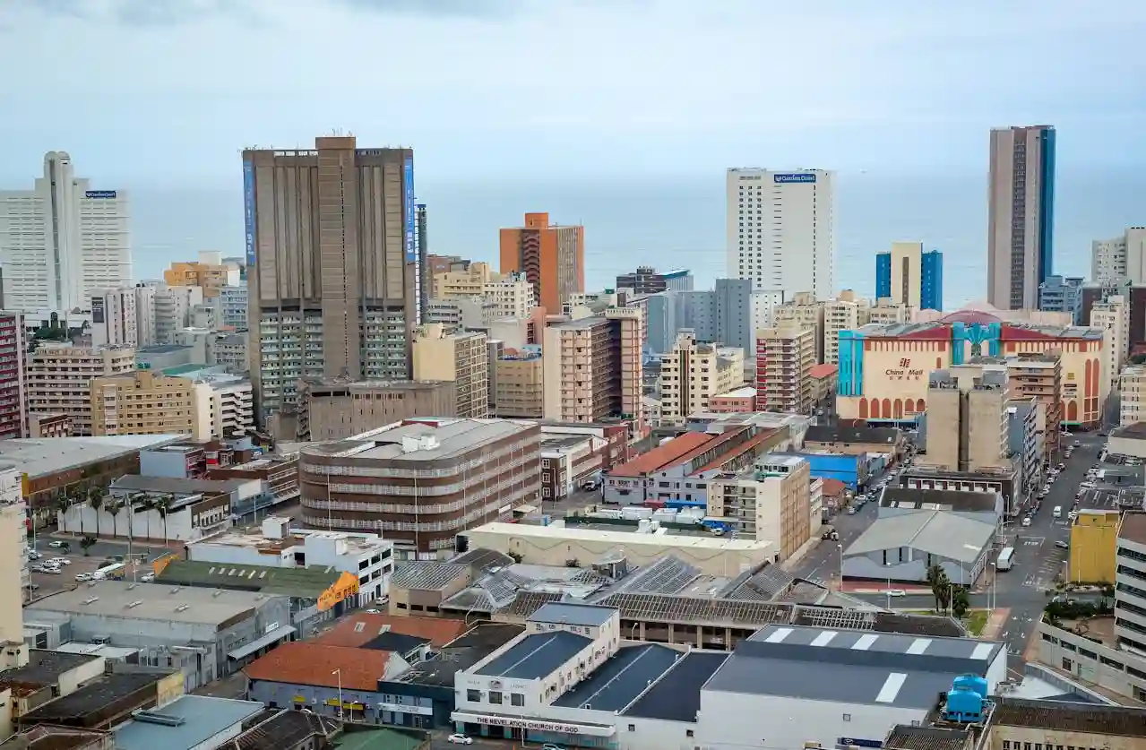 Aerial view of Durban, South Africa showing a dense skyline with various buildings and the ocean in the background.
