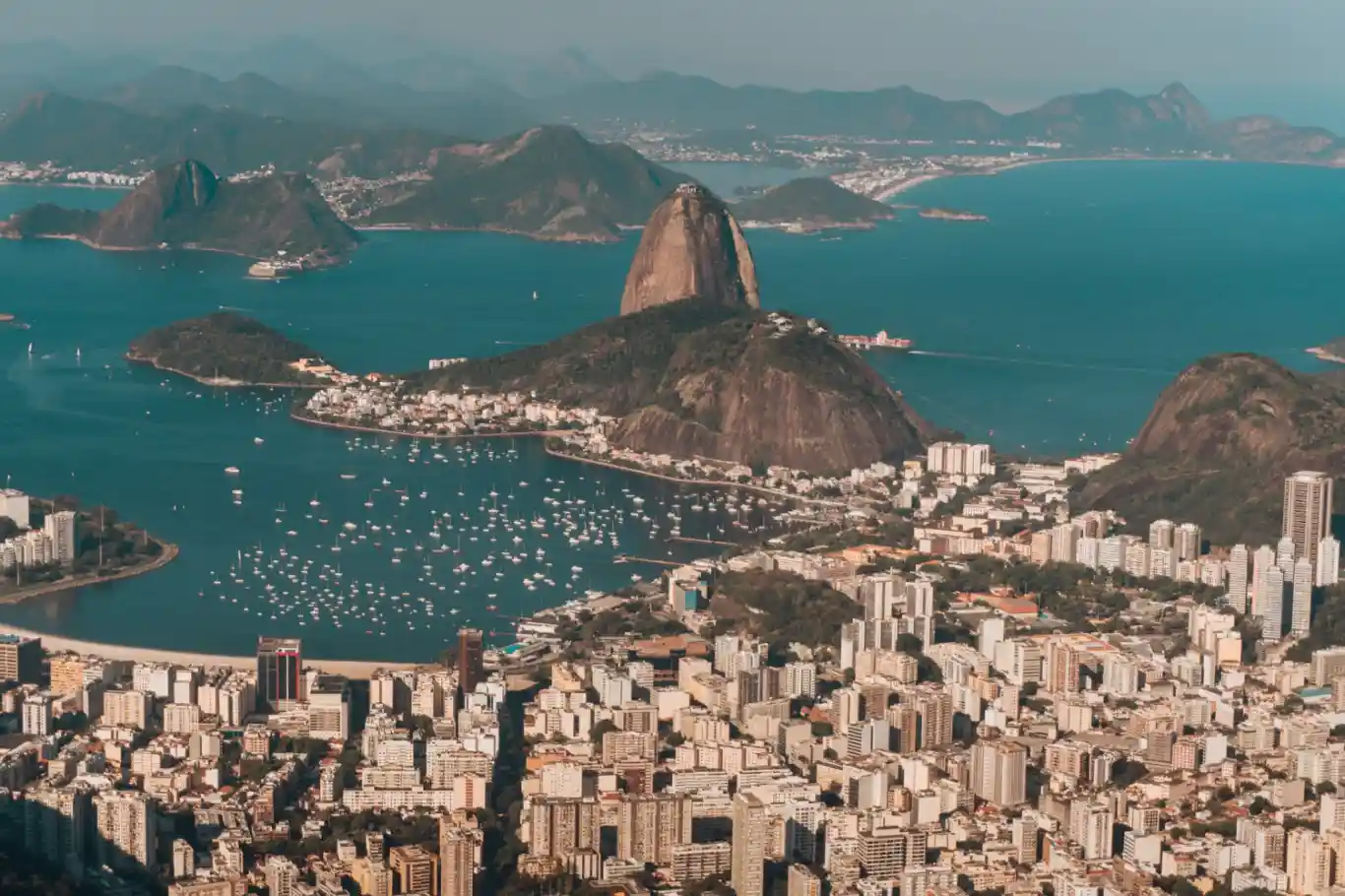 Aerial photo of Rio de Janeiro surrounded by hills and the sea under a blue sky in Brazil