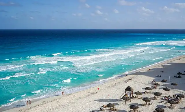 Scenic view of Cancun beachfront featuring rows of inviting sunbeds against the backdrop of the crystal-clear Caribbean Sea