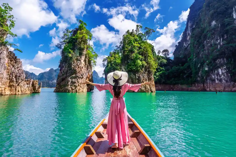 Girl standing on the boat and looking to mountains in Ratchaprapha Dam at Khao Sok National Park, Surat Thani Province, Thailand.