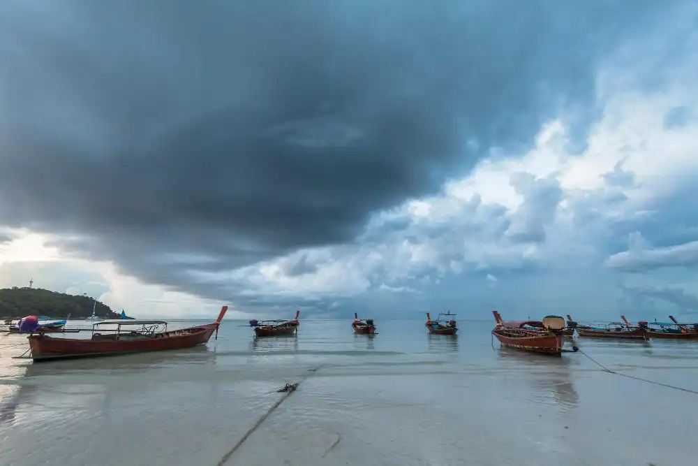 Boats in sea against dramatic sky