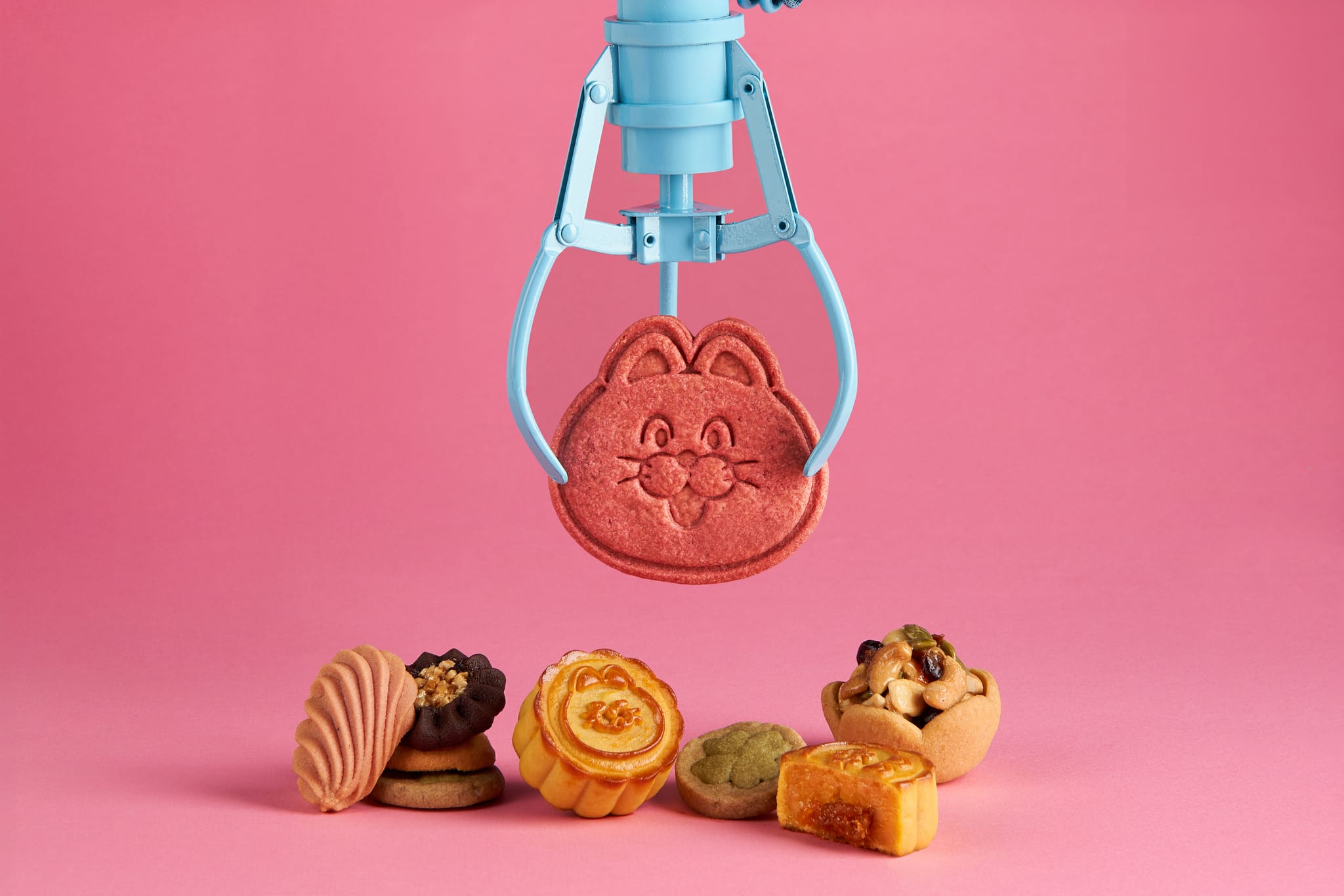 藍色夾娃娃機夾著粉色PINGO餅乾，粉色背景上擺放多款聯名新春餅乾。