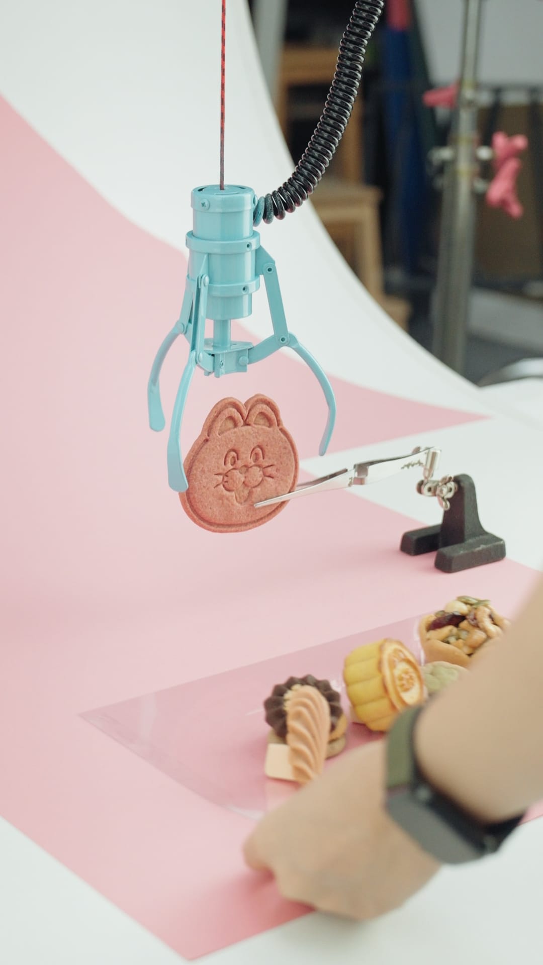 攝影師在粉色背景上使用賽璐璐片，避免餅乾油脂沾染，精準構圖。