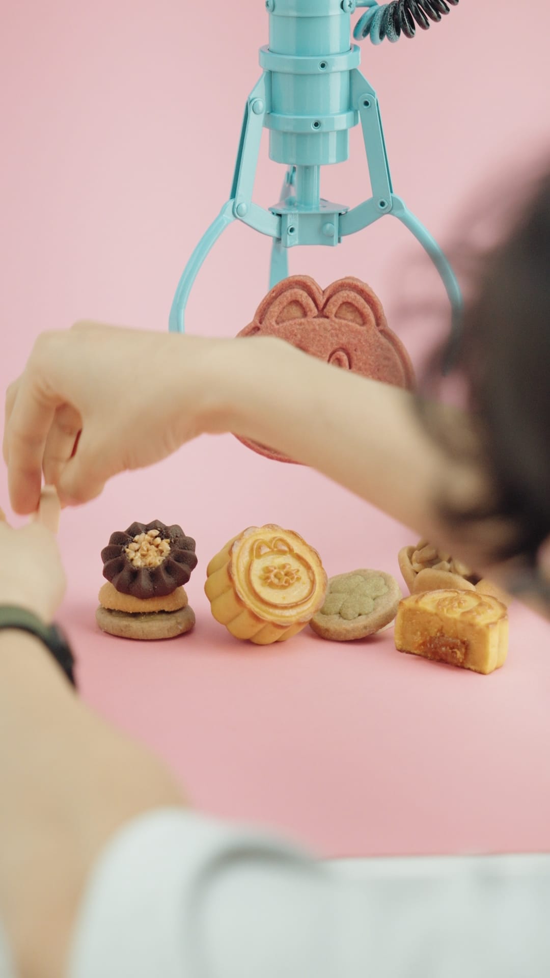 攝影師用夾娃娃機夾著PINGO餅乾，同時手動調整其他餅乾位置。
